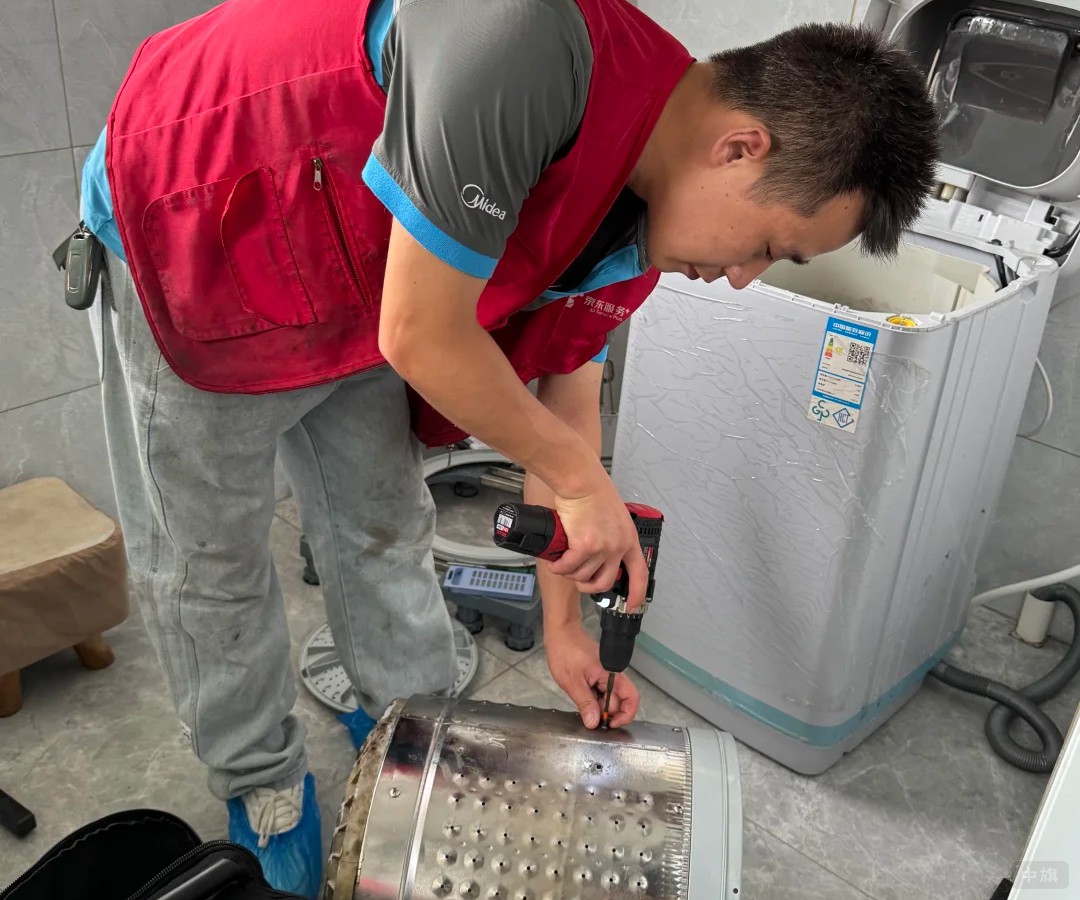 師傅在用電動(dòng)扳手拆洗衣機(jī)的滾筒